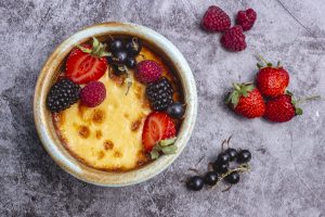 top view of crème brûlée garnished with strawberry raspberry black currant and blackberry